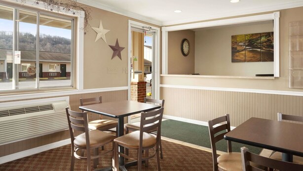 A dining area with a table and chairs, a window with a view, and a wall clock. - Super 8 by Wyndham Mifflinville Near Bloomsburg (Mifflinville)