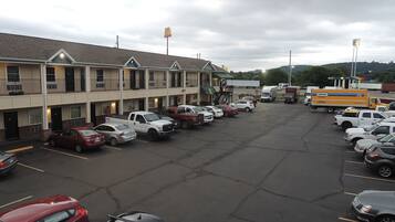 A multi-story motel with a parking lot filled with cars.