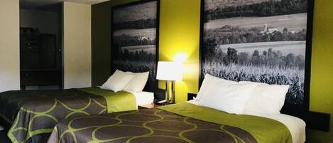 Habitación de hotel con dos camas, una mesita de noche, una lámpara y dos grandes cuadros con paisajes en las paredes.