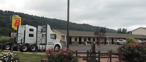 A motel with a large truck parked in front, a sign for 'Super 8' motel, and a 'Trip Ad Hall of Fame' sign.