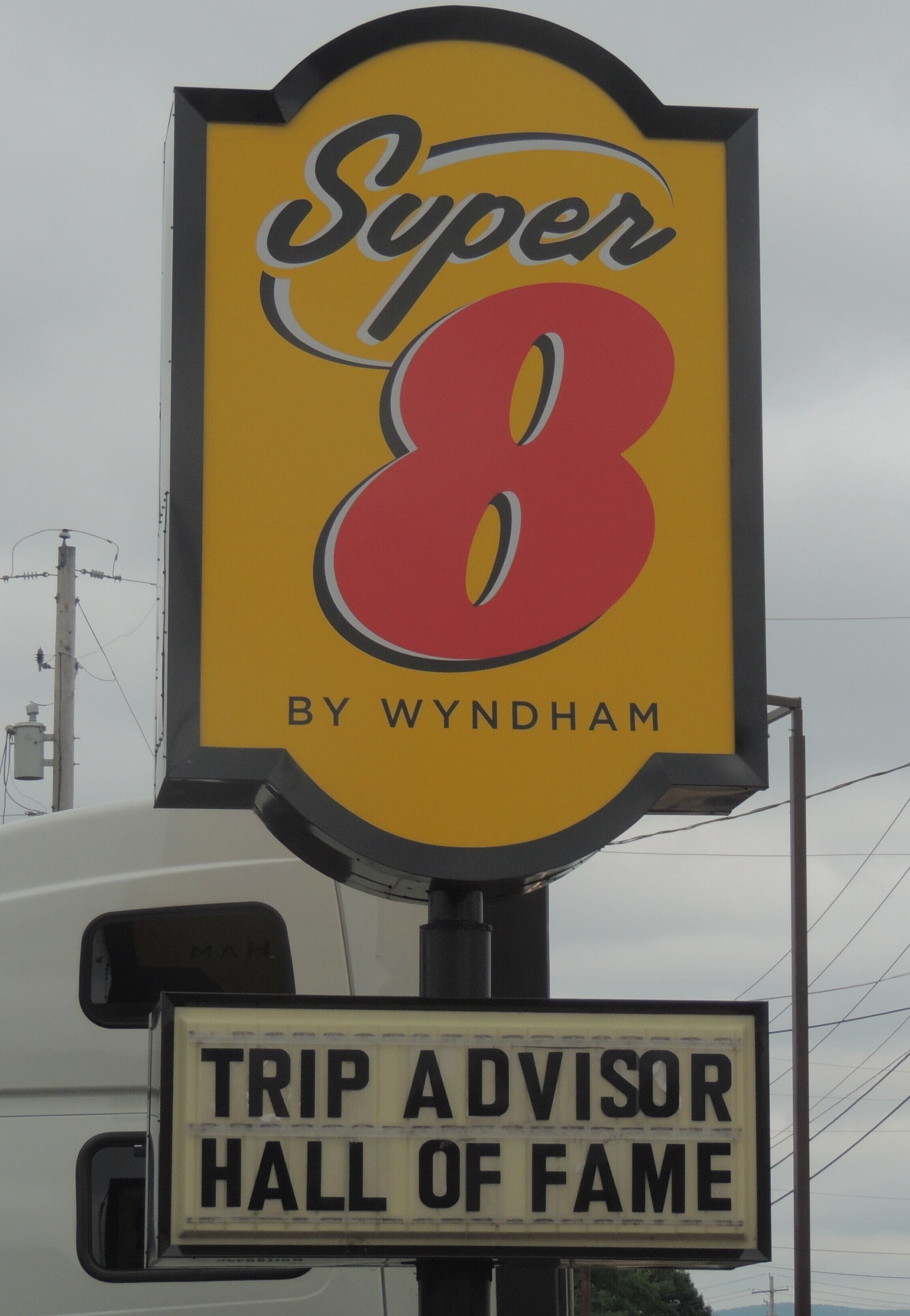 A sign with "Super 8 by Wyndham" and "TRIP ADVISOR HALL OF FAME" text.