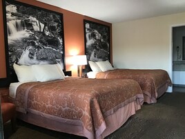 Habitación de hotel con dos camas, una mesita de noche, una lámpara y dos grandes cuadros enmarcados con paisajes de cascadas en las paredes.