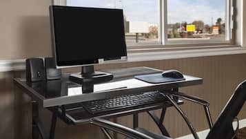 A computer desk with a monitor, keyboard, mouse, and speakers.
