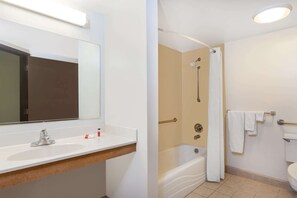 A bathroom with a sink, mirror, shower, and toilet. - Super 8 by Wyndham Harrisburg Hershey West (Harrisburg)