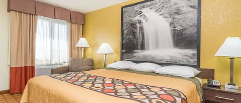 A hotel room with a large bed, two bedside lamps, a nightstand, and a large framed picture of a waterfall on the wall.