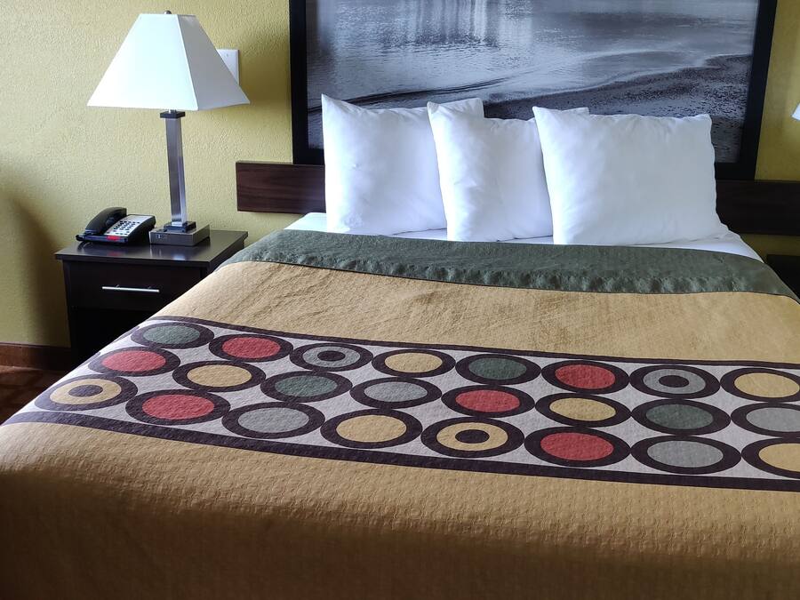 A hotel room with a bed, two bedside lamps, a telephone, and a chair.