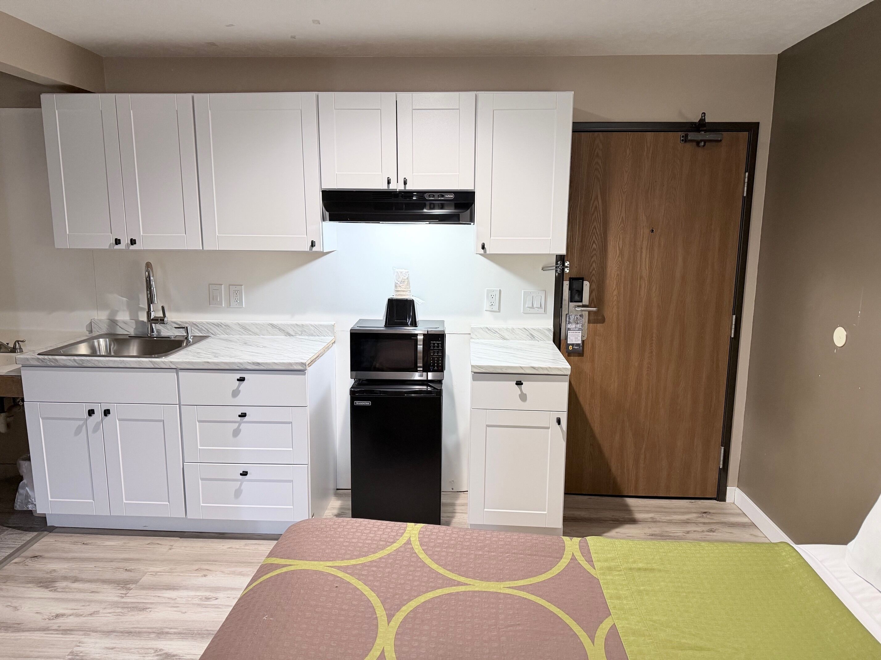 A compact kitchen with white cabinets, a built-in microwave, and a sink.