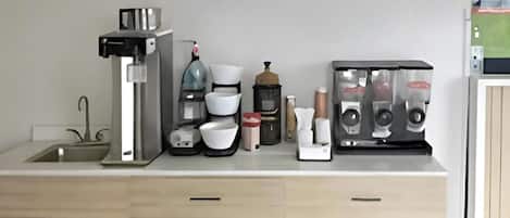 Een keukenblad met een koffiezetapparaat, een waterkoker, een koffiemolen, een broodrooster en een koffiemachine.