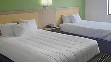 A hotel room with two beds, a nightstand, and a wall-mounted lamp.