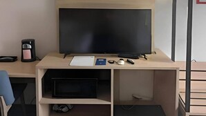 A modern office desk with a flat-screen monitor, a keyboard, a mouse, and a pair of glasses. - Park Inn by Radisson (Coraopolis)
