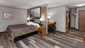 A hotel room with a bed, desk, chair, and a mirror.