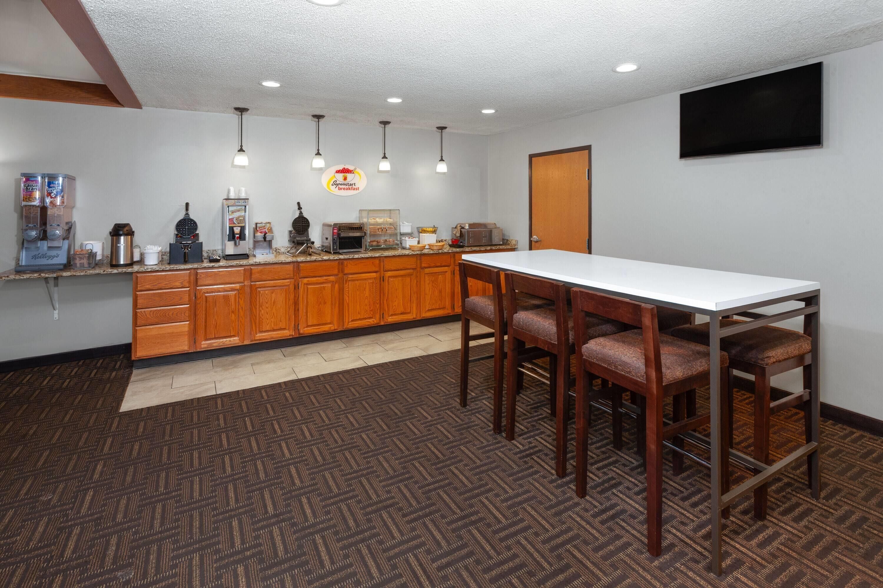 A kitchen with wooden cabinets, a white countertop, and a dining area with a table and chairs.