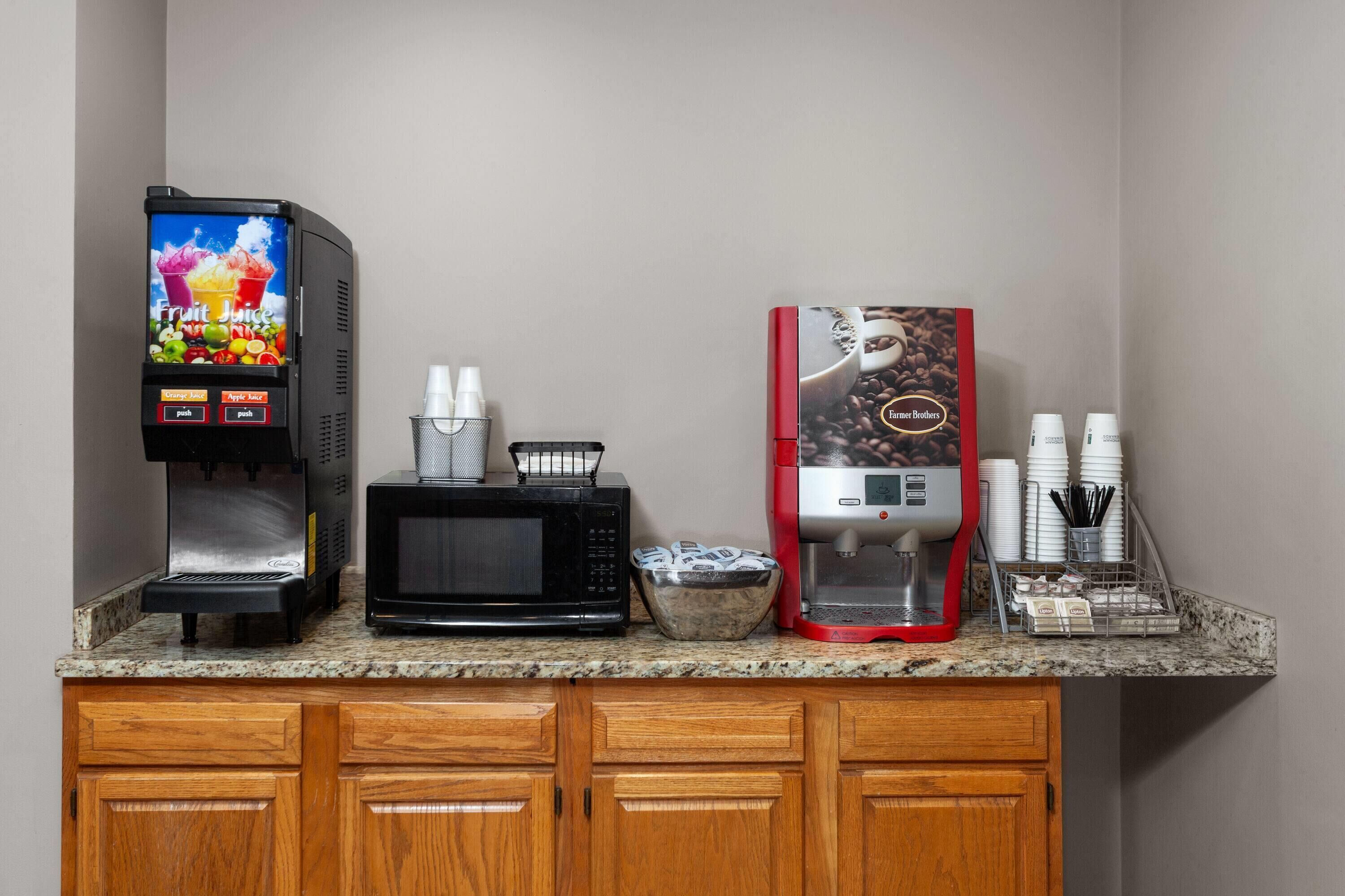 A kitchen counter with a fruit juice dispenser, a microwave, and a coffee machine.