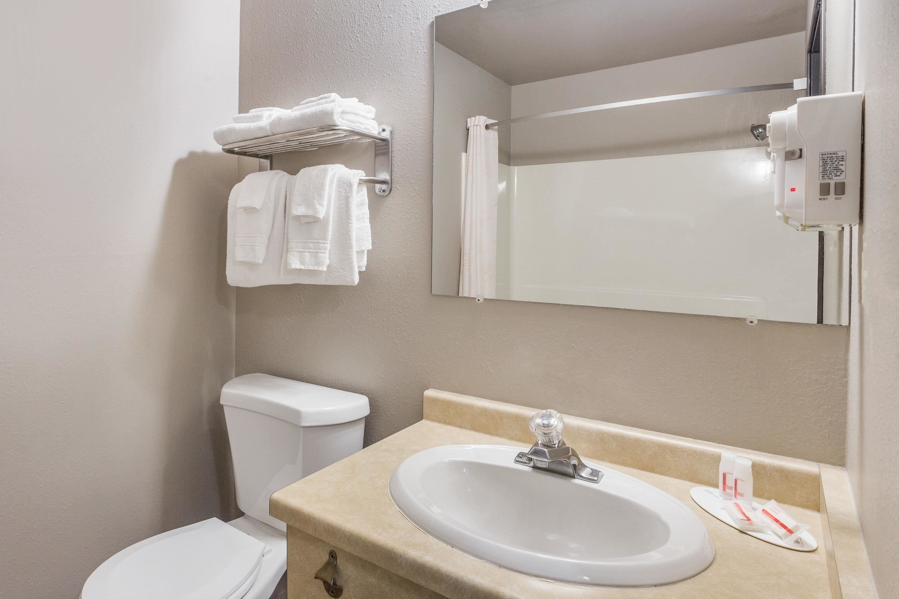 Un baño con inodoro, lavamanos y perchero para toallas.