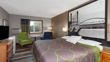 Een hotelkamer met een bed, twee stoelen, een bureau, een televisie en een groot raam.