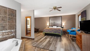 Una habitación de hotel con una cama grande, una bañera, un televisor y un cuadro de paisaje urbano en la pared.