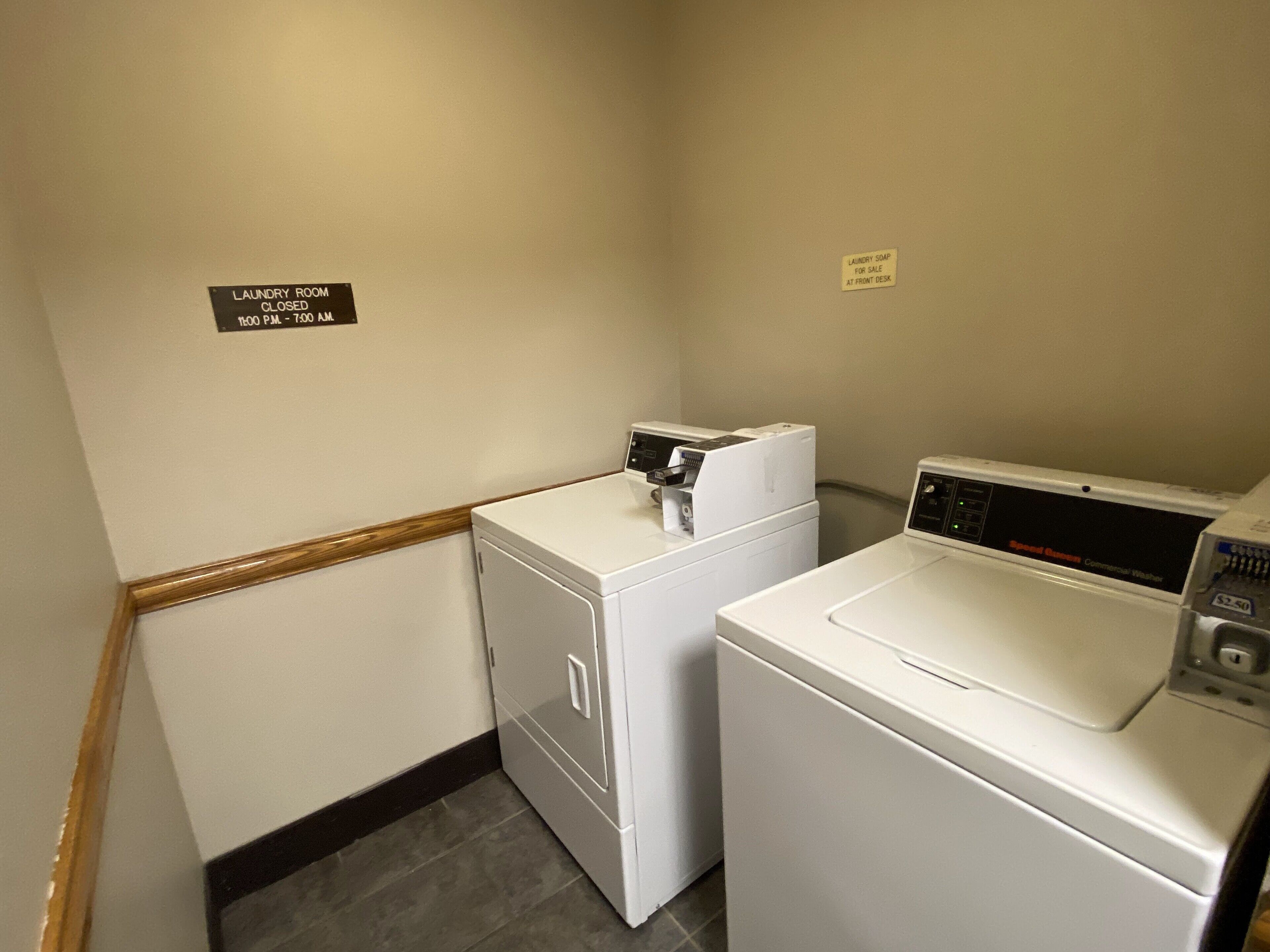 A laundry room with two washing machines and a closed sign on the wall.