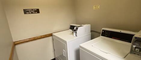 A laundry room with two washing machines and a closed sign on the wall.