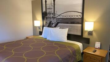 A hotel room with a bed, a nightstand, two wall-mounted lamps, and a large framed picture of a bridge.