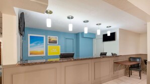 A reception area with a counter, a flat-screen TV, a chair, and artwork on the wall.