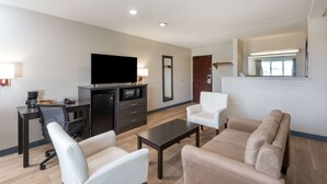 A modern living room with a flat-screen TV, a coffee machine, a microwave, a sofa, and a dining table.