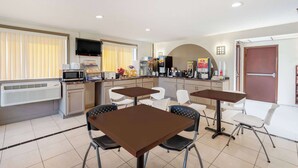 A modern kitchen with a microwave, toaster, and coffee maker. There are white chairs and a table in the dining area.