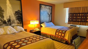 Ein Hotelzimmer mit zwei Betten, einem Nachttisch mit Lampe, einem Bild an der Wand und einem Fenster mit Vorhängen.