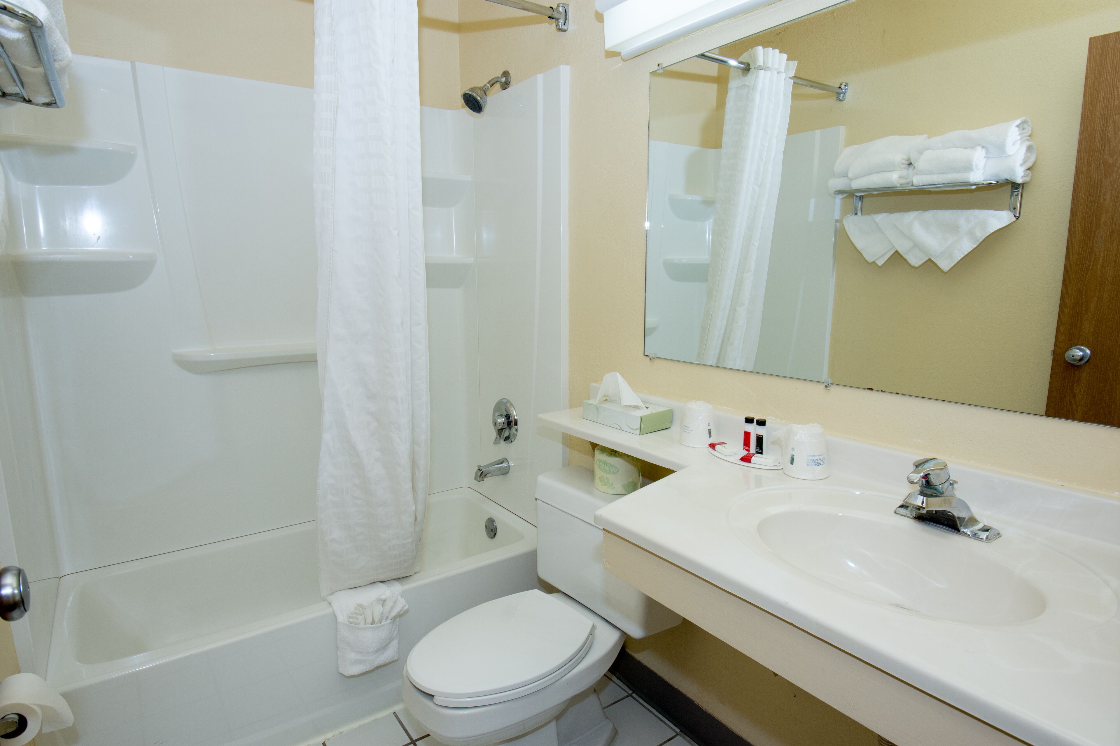 A bathroom with a bathtub, toilet, sink, and a mirror.