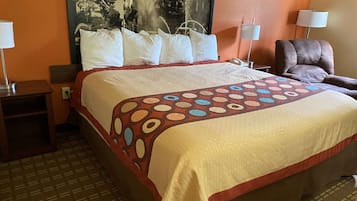 Une chambre d’hôtel avec un grand lit, deux tables de chevet, une chaise et un tableau au mur.