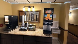 A coffee station with a coffee machine, cups, and a juice dispenser. - Fairview Inn & Suites Whitewater (Whitewater)
