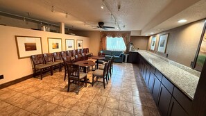 A spacious kitchen with a dining area, featuring a large island, dark cabinetry, and a tiled floor.