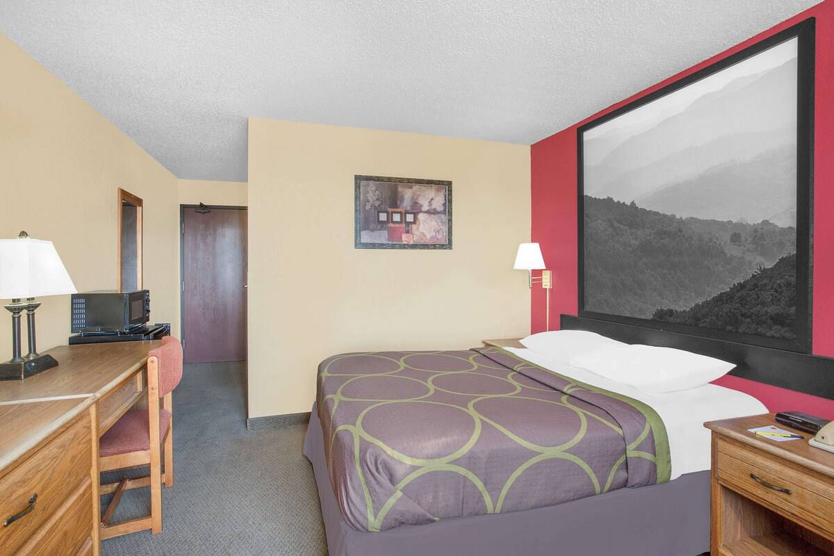 Ein Hotelzimmer mit Bett, Schreibtisch, Stuhl und einem großen Fenster mit Blick auf die Berge.
