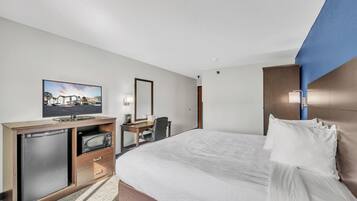 A hotel room with a bed, a desk, a television, and a minibar.