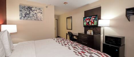 A hotel room with a bed, a desk, a television, and a microwave.