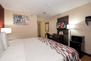 Una habitación de hotel con cama, escritorio, televisión y microondas.