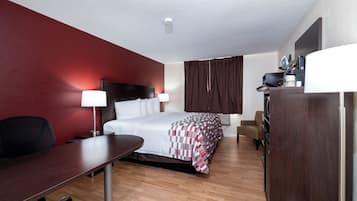 A hotel room with a bed, desk, chair, and a wardrobe.