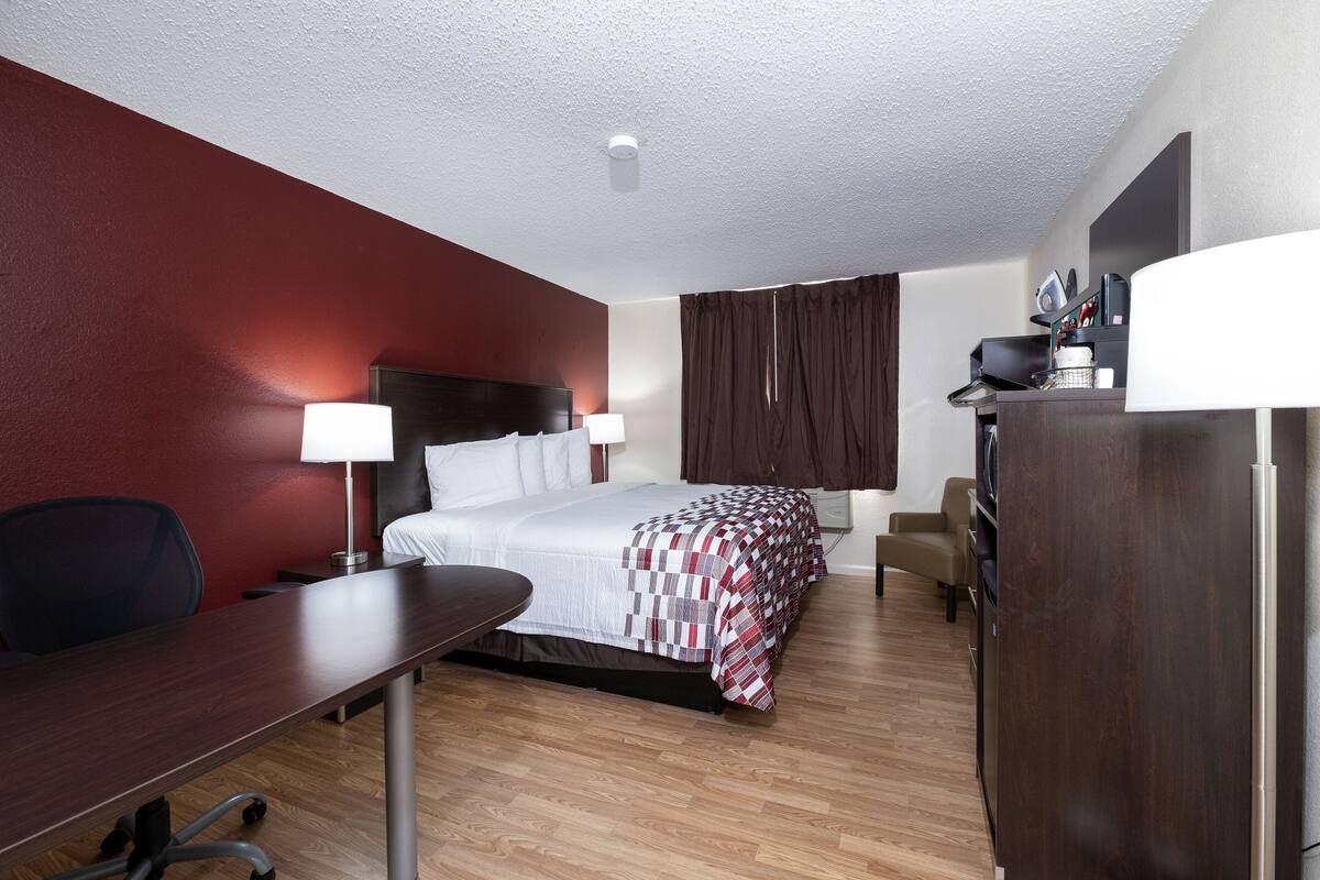 Una habitación de hotel con cama, escritorio, silla y armario.