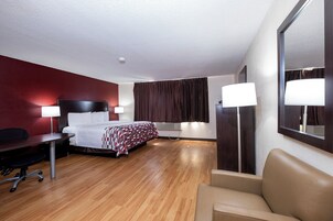 Habitación de hotel con cama, escritorio, silla y un espejo grande.
