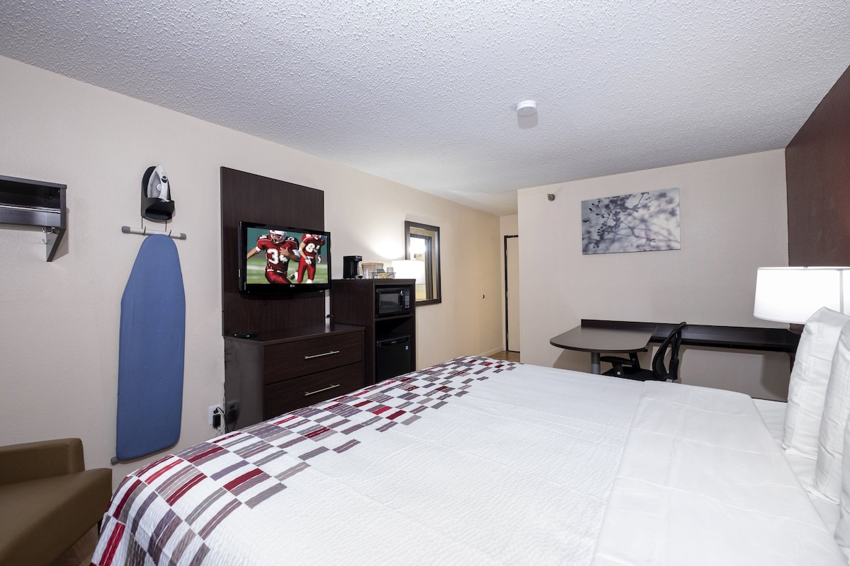 A hotel room with a bed, a desk, a TV, a microwave, and a coffee maker.