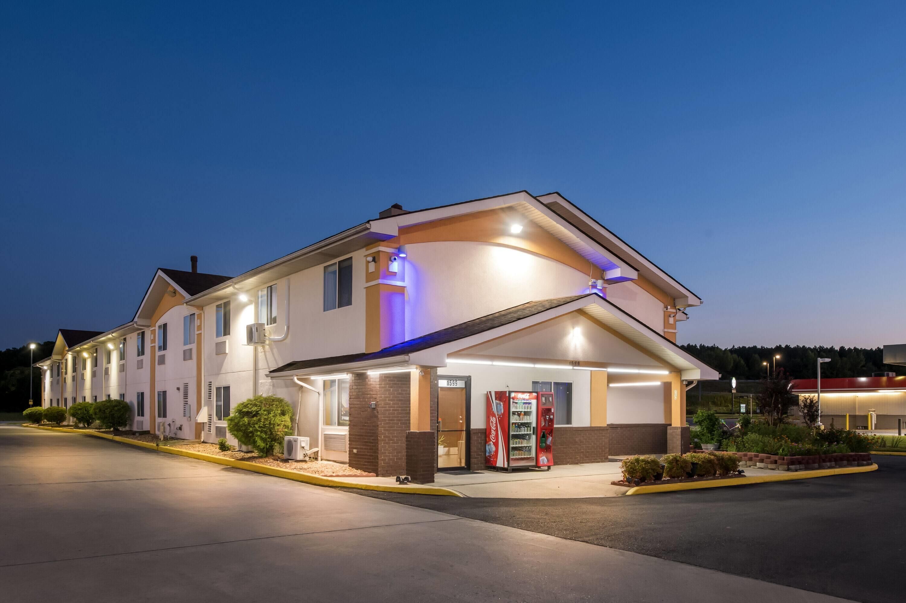 A hotel with a modern design, featuring a large entrance, a Coca-Cola vending machine, and a well-lit exterior.