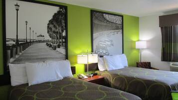 Una habitación de hotel con dos camas, un cuadro grande enmarco de una pista de carreras, una lámpara y una ventana con cortinas.