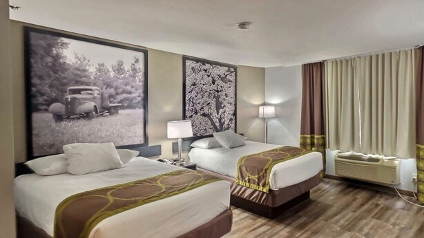 A hotel room with two beds, a large framed picture on the wall, a bedside table with a lamp, and a window with curtains. - Super 8 by Wyndham Georgetown (Georgetown)