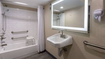 A bathroom with a bathtub, a sink, a mirror, a shower, and a hairdryer.