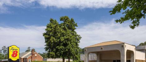 A Super 8 motel with a large tree, a covered parking area, and a landscaped garden.