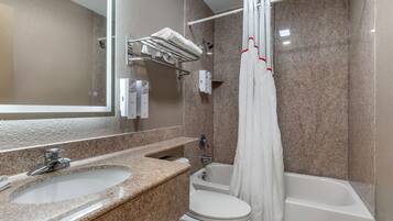 A bathroom with a granite countertop sink, a toilet, and a bathtub with a shower curtain.