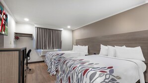 A hotel room with a long bed, a desk, and a chair. - Red Roof Inn Suffolk (Suffolk)