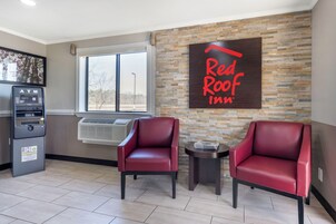 Vestíbulo de Red Roof Inn con dos sillones de cuero, un cajero automático y una pared de piedra.