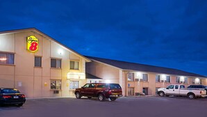 Un hotel Super 8 con un estacionamiento, una camioneta SUV color borgoña y una camioneta pickup blanca estacionadas al frente.
