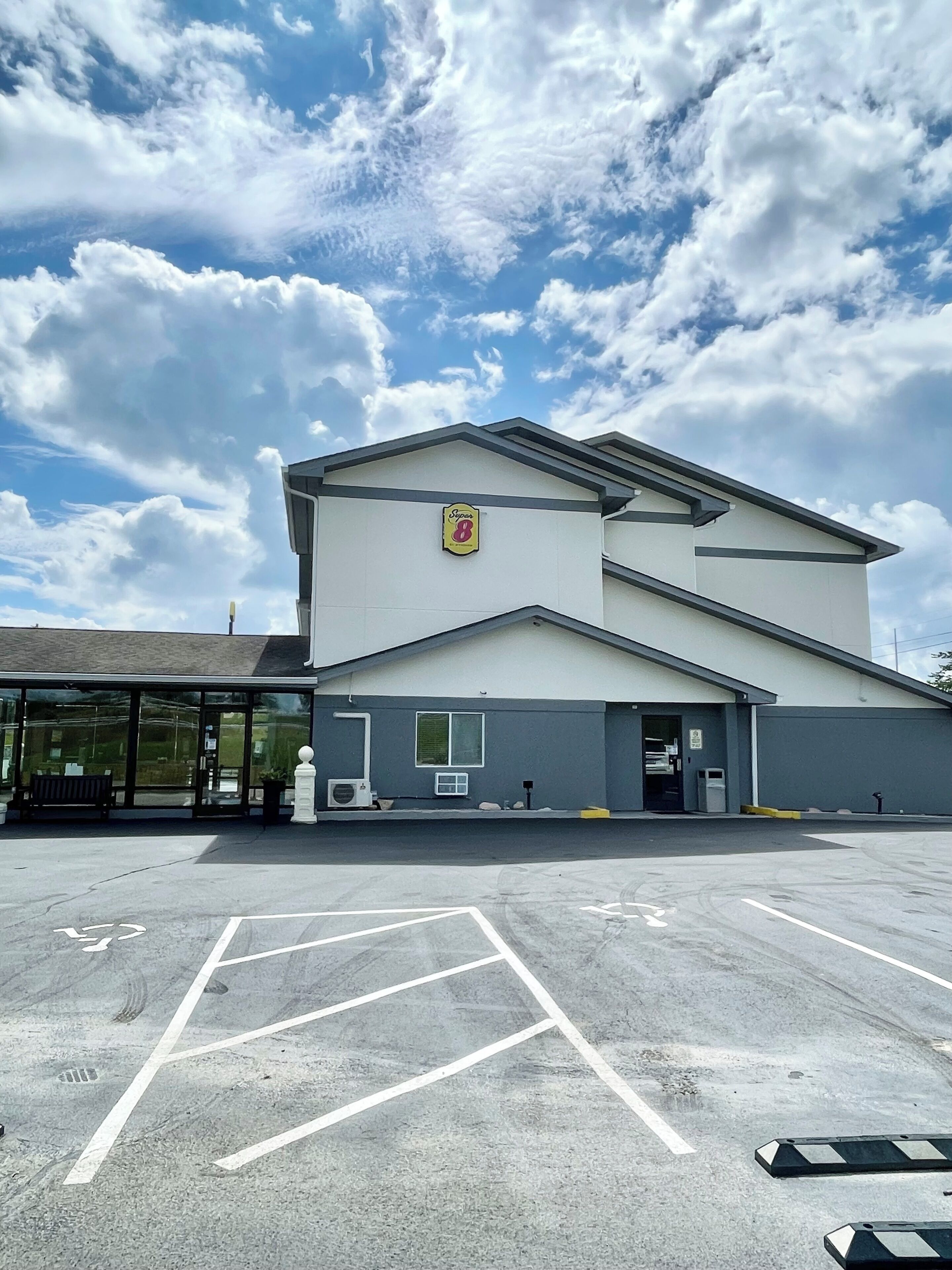 A building with a large parking lot, a sign with the number 8, and a clear sky with clouds.