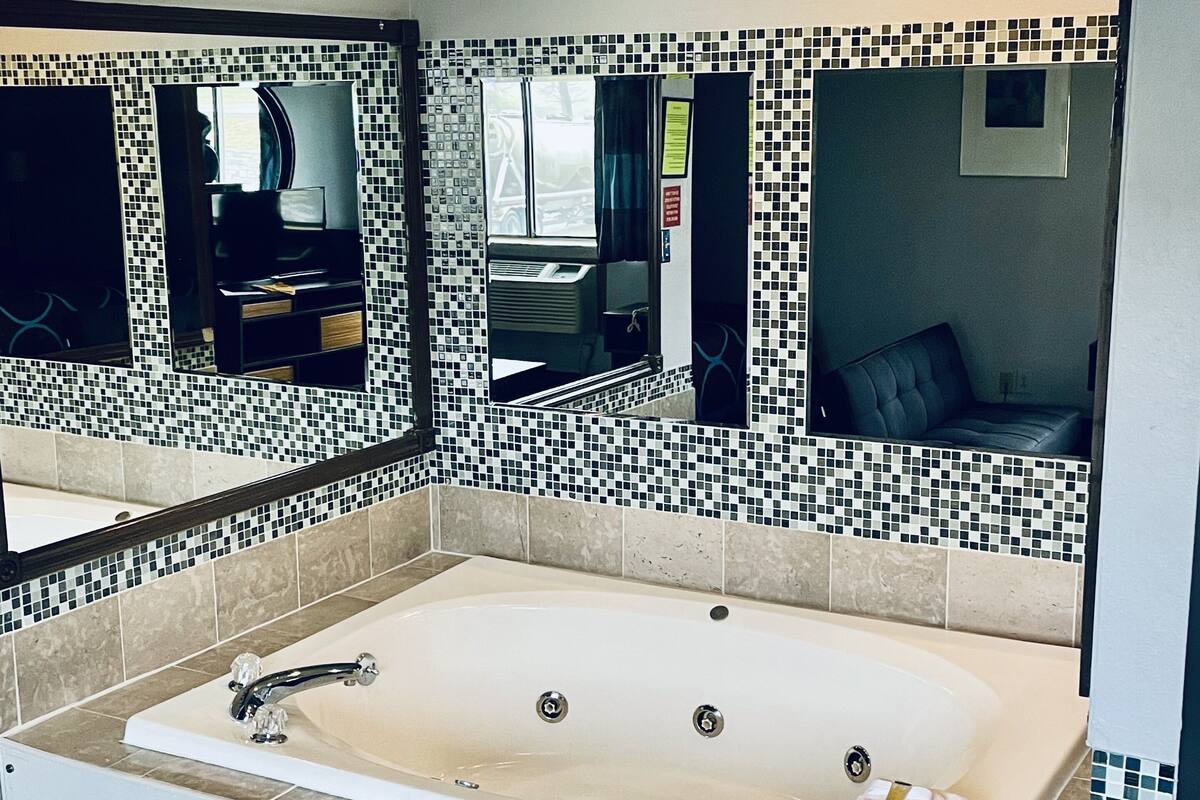 Un baño moderno con una bañera grande, un tocador con espejo y un salpicadero de azulejos.